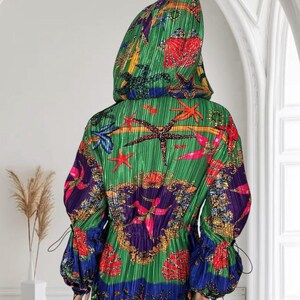 May include: A hooded jacket with a pleated texture, featuring a vibrant green base with a colorful print of red, orange, and blue starfish, seashells, and ornate gold-toned patterns. The jacket has long sleeves with adjustable drawstring cuffs.