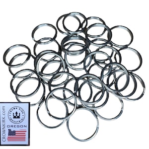 May include: A pile of 30 silver key rings. The key rings are all the same size and are made of metal. The key rings are arranged in a random pattern.