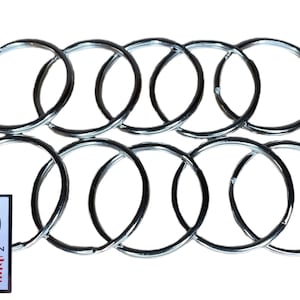 May include: Ten silver key rings, all the same size, are arranged in a circle. The rings are made of metal and have a smooth, shiny finish.