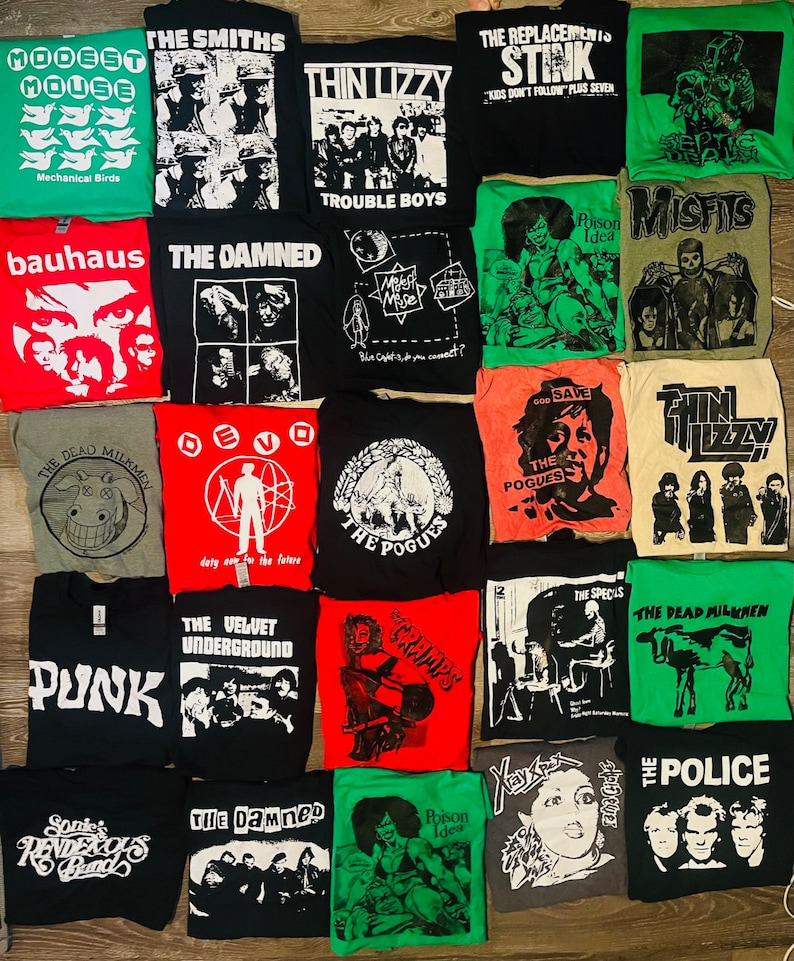 May include: A selection of band t-shirts, showcasing designs for various rock and punk bands. The shirts are in different colours, with graphics and band names including "The Smiths", "The Damned", and "The Police".
