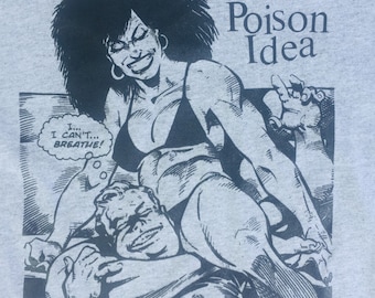 May include: A light gray t-shirt featuring a black and white comic book style illustration. The graphic depicts a muscular woman with a large afro, sitting on top of a man. The text "Poison Idea" is above the illustration.