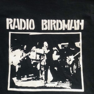 May include: Black and white graphic t-shirt with the text "RADIO BIRDMAN" printed on the front. The graphic features a band performing on stage.