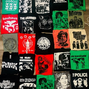 May include: A selection of band t-shirts in various colours, including black, red, green, and grey. The shirts feature band names and graphics such as "The Smiths," "Thin Lizzy," "The Damned," and "The Pogues." The shirts are laid out flat.