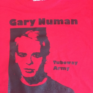 Könnte beinhalten: Rotes T-Shirt mit einem Schwarzweißbild von Gary Numan und dem Text "Gary Numan Tubeway Army".