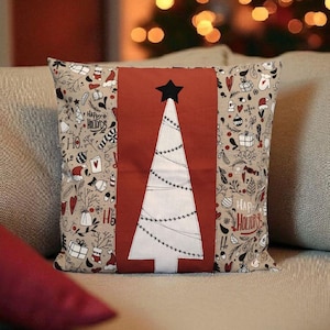 May include: Square cushion with a Christmas tree design. It features a white tree with string lights on a red panel, topped with a black star. The sides have a beige pattern with festive motifs. The words "Happy Holidays" are visible.