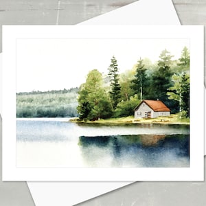 May include: Watercolor painting of a lakeside cabin with a red roof, surrounded by green trees. The cabin is situated on the edge of a calm lake, with reflections of the trees and cabin in the water. The artwork is on a white card.