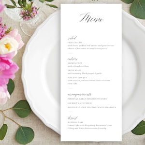 May include: A white menu card with black text listing the menu items for a wedding reception. The menu includes salad, entrees, accompaniments, and dessert. The menu items are: Fazeli Salad, Salmon Filet, The-Tip Roast, Poblano Chicken, Parmesan Garlic Mashed Potatoes, Gourmet Mac & Cheese, Ratatouille Style Vegetables with Asparagus, and Wedding Cake.