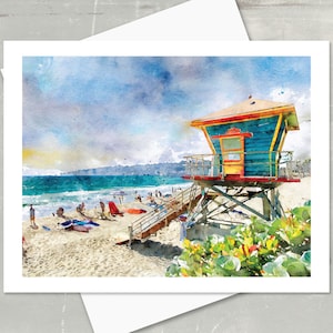 May include: Watercolor print of a beach scene featuring a lifeguard tower. The tower is painted in shades of blue, red, and yellow, with a wooden staircase leading to the sandy beach. People are relaxing on the beach and in the water under a blue sky.