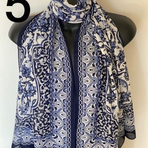 Peut inclure: Une &eacute;charpe &agrave; motifs bleus et blancs avec un motif floral. L'&eacute;charpe a une bordure bleu marine.
