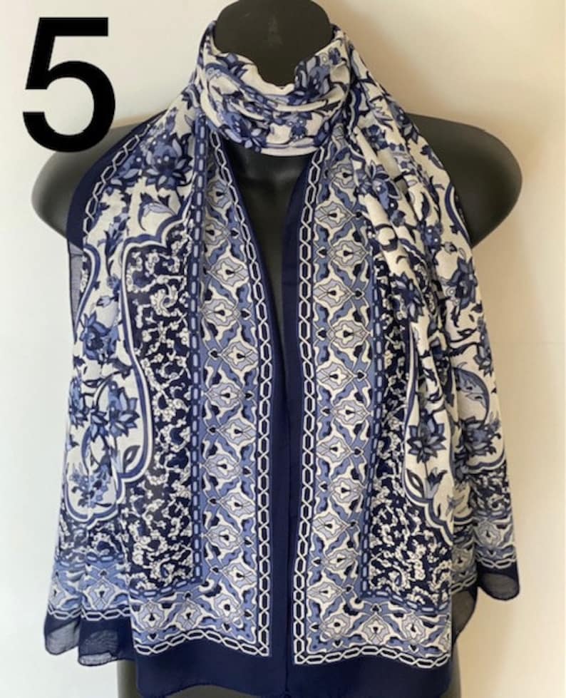 Peut inclure: Une &eacute;charpe &agrave; motifs bleus et blancs avec un motif floral. L'&eacute;charpe a une bordure bleu marine.