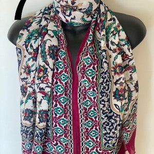 Peut inclure: Une &eacute;charpe &agrave; motifs blancs et bordeaux avec un design g&eacute;om&eacute;trique. L'&eacute;charpe pr&eacute;sente un motif floral avec des accents verts, rouges et bleus.