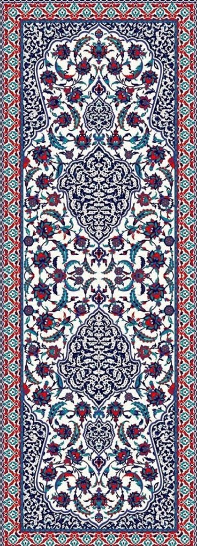 Peut inclure: Un tapis blanc avec un motif floral bleu et rouge. Le tapis a une bordure avec un motif g&eacute;om&eacute;trique.