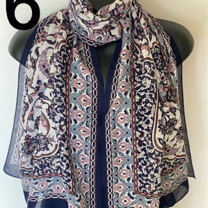Peut inclure: Une &eacute;charpe &agrave; motifs bleu marine et blanc avec des accents roses et bleus. L'&eacute;charpe a un motif g&eacute;om&eacute;trique avec des d&eacute;tails floraux.