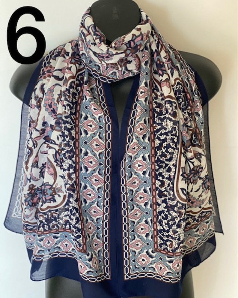 Peut inclure: Une &eacute;charpe &agrave; motifs bleu marine et blanc avec des accents roses et bleus. L'&eacute;charpe a un motif g&eacute;om&eacute;trique avec des d&eacute;tails floraux.