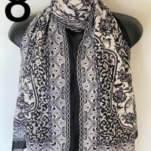 Peut inclure: &Eacute;charpe en soie &agrave; motifs noir et blanc avec un design g&eacute;om&eacute;trique. L'&eacute;charpe est pli&eacute;e et drap&eacute; sur un mannequin.
