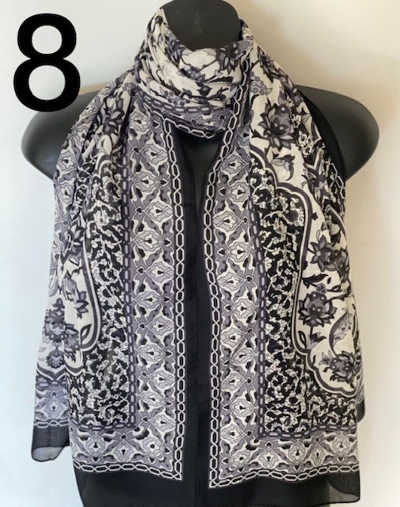 Peut inclure: &Eacute;charpe en soie &agrave; motifs noir et blanc avec un design g&eacute;om&eacute;trique. L'&eacute;charpe est pli&eacute;e et drap&eacute; sur un mannequin.