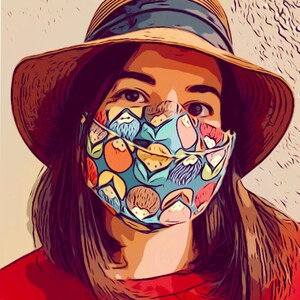 K&ouml;nnte beinhalten: Eine Frau tr&auml;gt einen Strohhut mit einem blauen Band und eine blaue und gr&uuml;ne gemusterte Gesichtsmaske mit bunten Fr&uuml;chten und Blumenmustern.