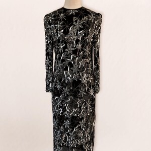 May include: A black long-sleeved dress with a silver floral pattern. The dress is made of a sheer fabric and is embellished with sequins.