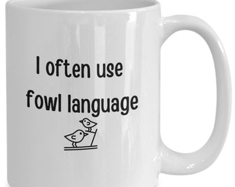 May include: White ceramic mug with a black text that reads "I often use fowl language" and a small illustration of two birds. The mug has a curved handle and is designed for hot beverages.