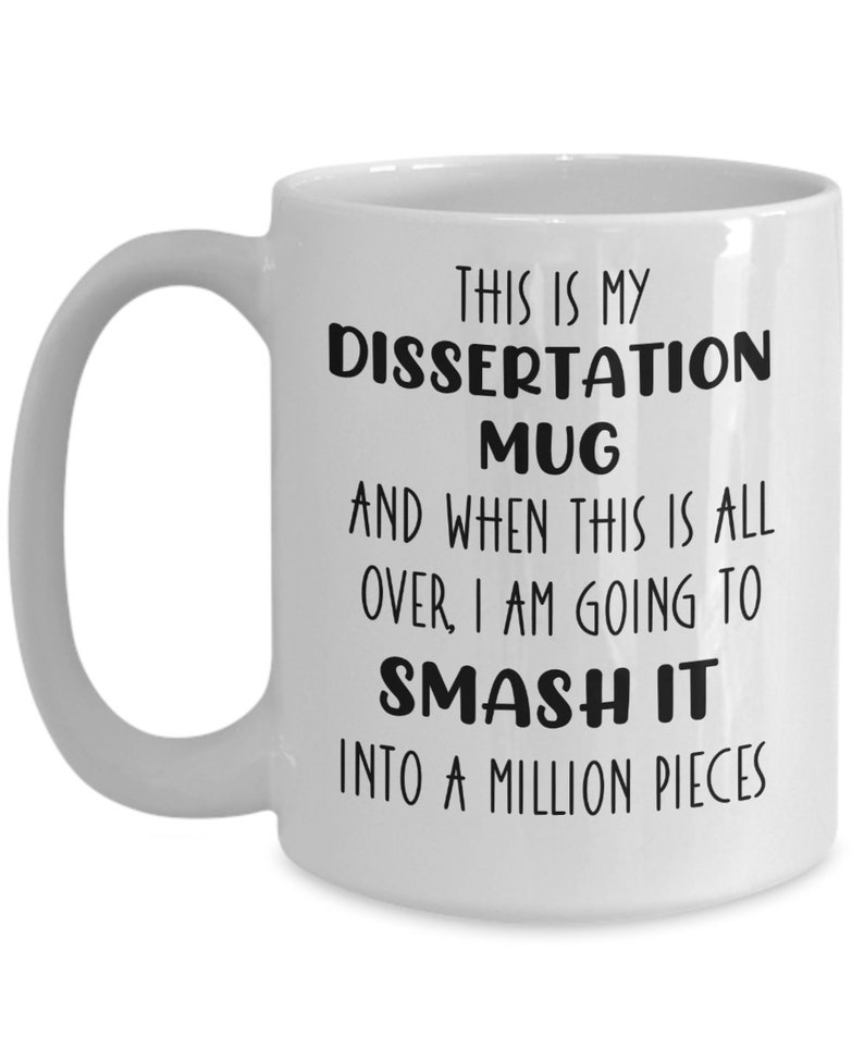 May include: White ceramic mug with a curved handle. The mug features black text that reads: "THIS IS MY DISSERTATION MUG AND WHEN THIS IS ALL OVER, I AM GOING TO SMASH IT INTO A MILLION PIECES."