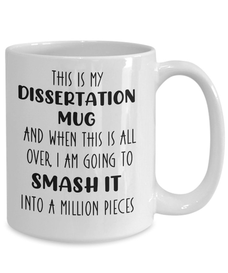 May include: White ceramic mug with a curved handle. The mug features black text that reads: "THIS IS MY DISSERTATION MUG AND WHEN THIS IS ALL OVER, I AM GOING TO SMASH IT INTO A MILLION PIECES."