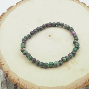 May include: A green and pink gemstone bracelet with round beads.