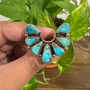May include: A silver ring featuring a crescent-shaped arrangement of six teardrop-shaped turquoise stones. The stones are set in individual silver bezels with small silver bead accents between them and a twisted silver wire detail.