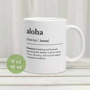 Puede incluir: Taza de cerámica blanca con una definición en negro de la palabra "aloha" en hawaiano. La taza está disponible en tamaños de 11 oz y 15 oz.