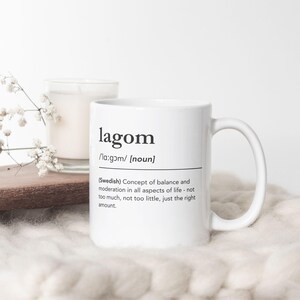 Può includere: Tazza in ceramica bianca con una definizione in bianco e nero della parola svedese "lagom", che significa "la giusta quantità".
