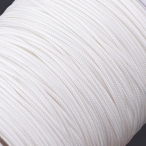 May include: Close-up of a spool of white cord. The cord is smooth and tightly wound.