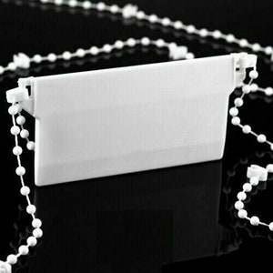 May include: White plastic blind chain holder with a white beaded chain. The chain holder is designed to hold the chain in place when not in use.
