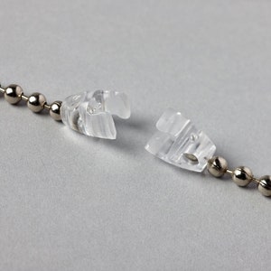 May include: A close-up of a silver beaded chain with two clear plastic connectors. The connectors are separated, showing the chain is broken.