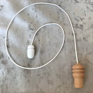 Puede incluir: Cordón blanco con una cuenta de tracción de plástico blanco en un extremo y una cuenta de tracción de madera en el otro extremo.