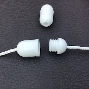 May include: White plastic cord end caps for a window blind or curtain. The end cap is threaded and can be screwed onto the cord.