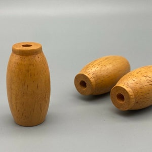 Op de afbeelding: Drie houten eindstukken in een lichtbruine kleur. De eindstukken zijn ovaalvormig met een gat in het midden.