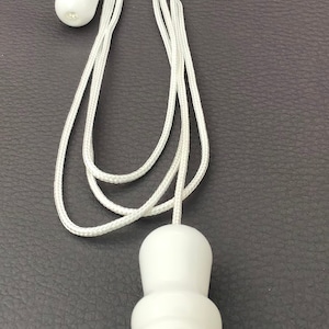 May include: A white, decorative light pull with a matching cord and a small, round pull. The main pull is a rounded, bulbous shape. The cord is white and looped.