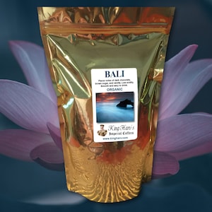 May include: A gold foil bag of Bali coffee beans. The bag has a label with the text "BALI" and "ORGANIC" and a picture of a beach scene. The label also includes the text "King Hari's Imperial Coffees" and "www.kingharv.com".