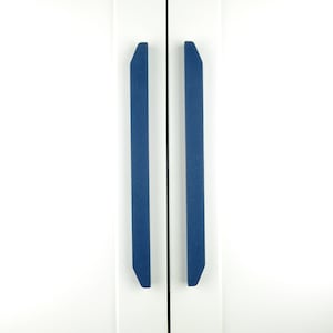 May include: Two blue cabinet door pulls with a rectangular shape and rounded edges.