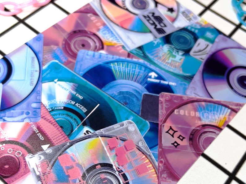 May include: A collection of colorful mini CDs and cases in shades of blue, pink, and purple. Some cases have text like "NEO ZONE" and "COLOR PALETTE". The image has a retro, Y2K aesthetic.