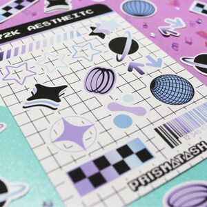 May include: A sheet of stickers with a Y2K aesthetic theme. The stickers feature a variety of designs, including stars, planets, and geometric shapes. The stickers are printed on white paper with a grid pattern. The text "Y2K AESTHETIC" and "PRISMATASH" are printed on the sheet.