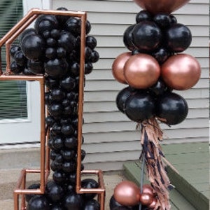 Puede incluir: Un gran globo de color oro rosa con el texto "You're the One Happy Anniversary" en escritura negra. Un arco de globos negro y oro rosa en forma del n&uacute;mero uno.