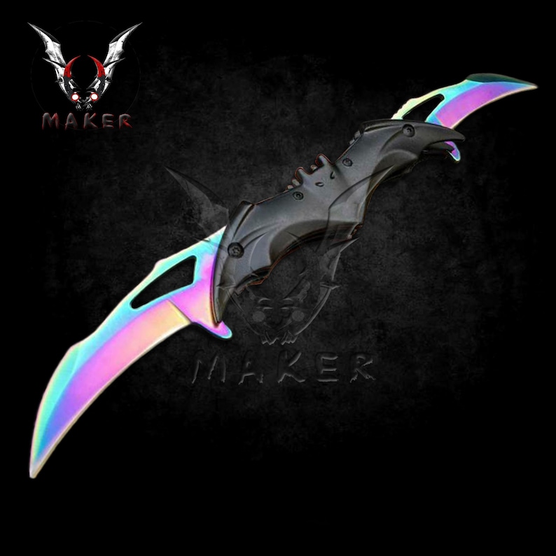 Puede incluir: Un cuchillo de doble filo negro e iridiscente con un mango en forma de murci&eacute;lago. El cuchillo est&aacute; abierto y las hojas son afiladas.