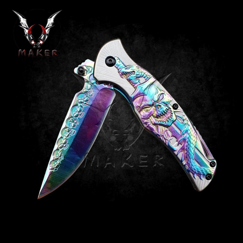May include: A rainbow-coloured folding pocket knife with a skull and snake design on the blade. The knife is open and the blade is partially extended.