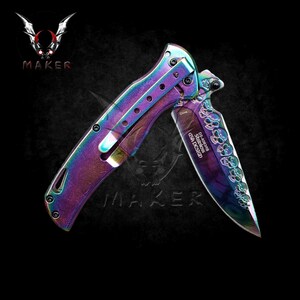May include: A rainbow-coloured folding knife with a skull design on the blade. The blade is engraved with "DS-A3488 Stainless USA Design".