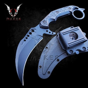 May include: A black karambit knife with a textured handle and a finger ring. The knife comes with a black plastic sheath with a belt clip.