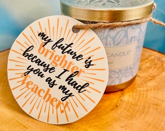 May include: A round, cream-colored tag with a sunburst design and the text "my future is brighter because I had you as my teacher!"
