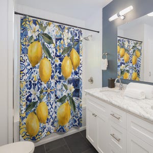 May include: A shower curtain featuring a watercolor design of lemons and leaves against a blue and white tile pattern. The lemons are yellow, and the leaves are green. The curtain adds a touch of freshness to any bathroom.