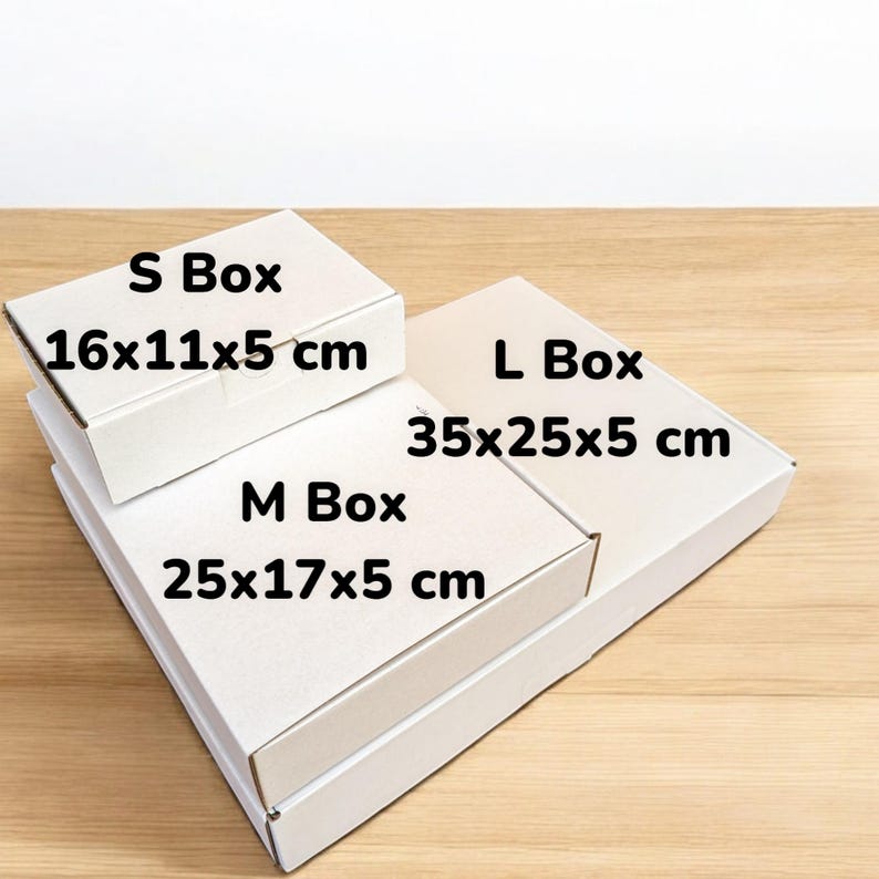 May include: Three white cardboard boxes stacked on top of each other. The top box is labeled "S Box 16x11x5 cm", the middle box is labeled "M Box 25x17x5 cm", and the bottom box is labeled "L Box 35x25x5 cm".