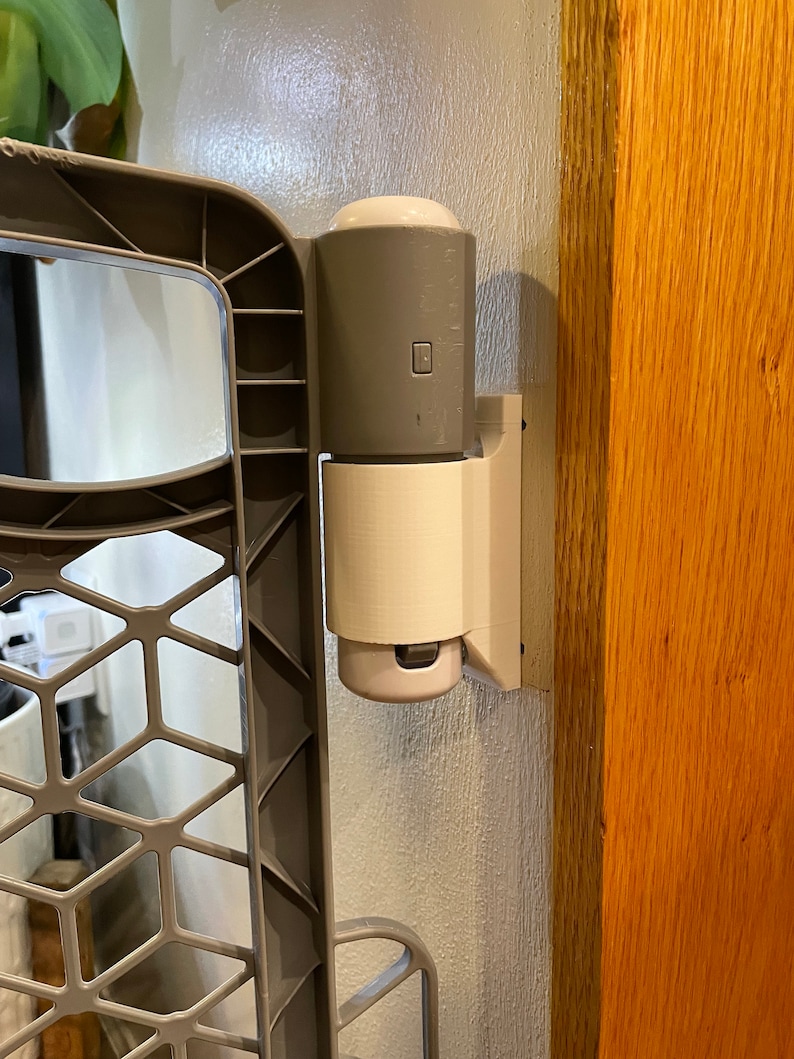 May include: A gray baby gate with a white plastic latch attached to a wooden door frame.