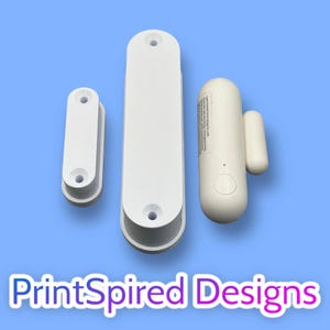 May include: Three white, oblong security system components are arranged on a blue background. The components include two elongated pieces with mounting holes and a rounded device with a smaller, rectangular piece. The text "PrintSpired Designs" is at the bottom.